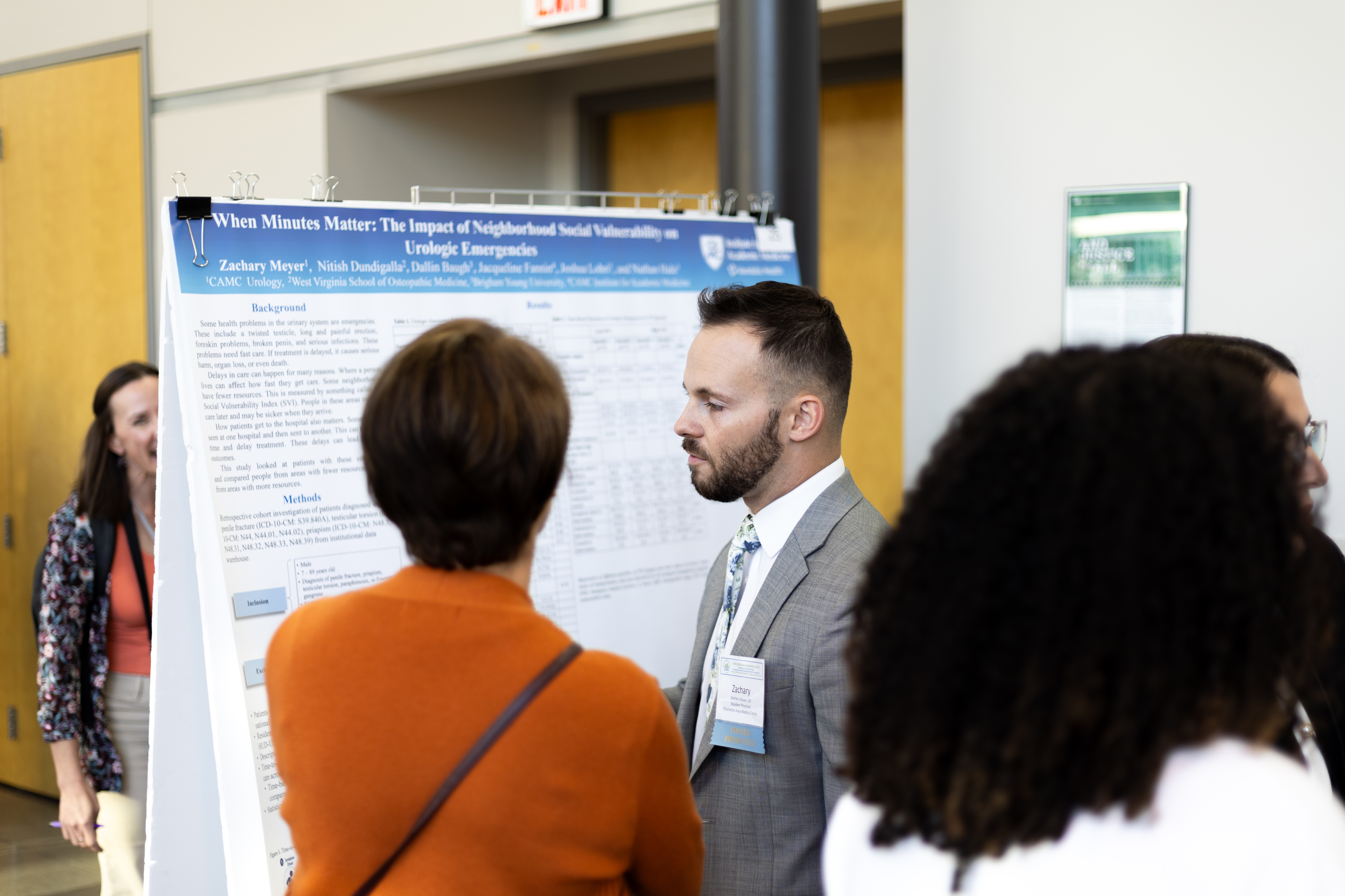 Researchers explaining their research poster to attendees