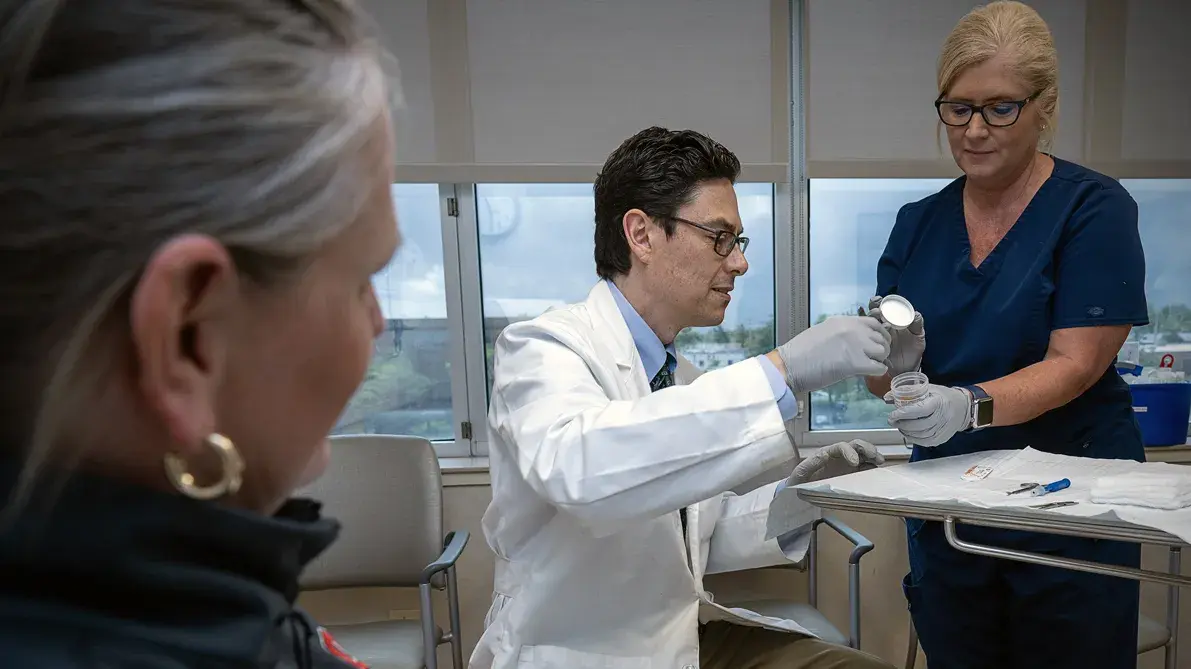 male researcher in a white lab coat is helped by his assistant in collecting a blood sample