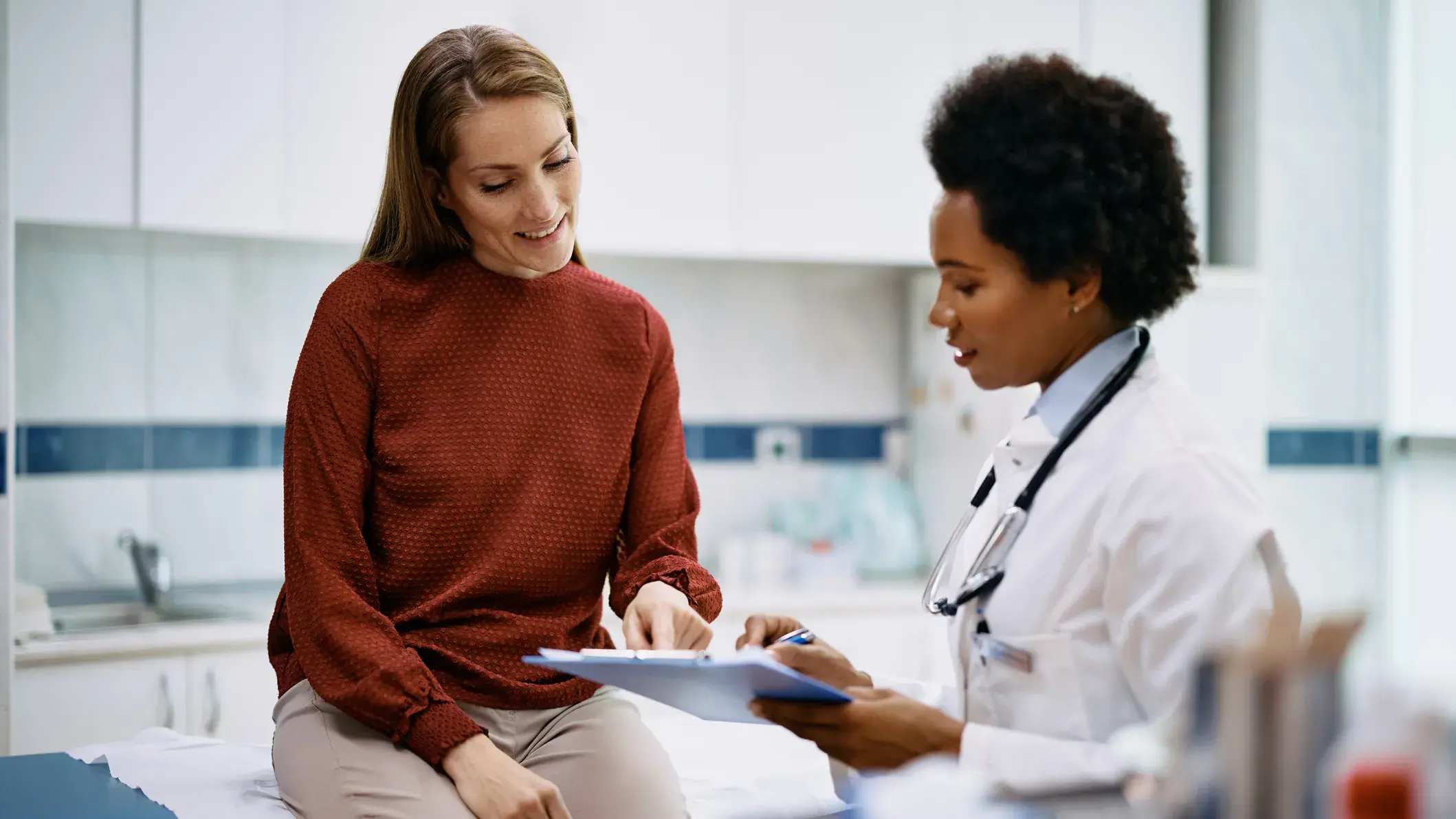 A doctor holding a clipboard while a nearby patient reviews the contents