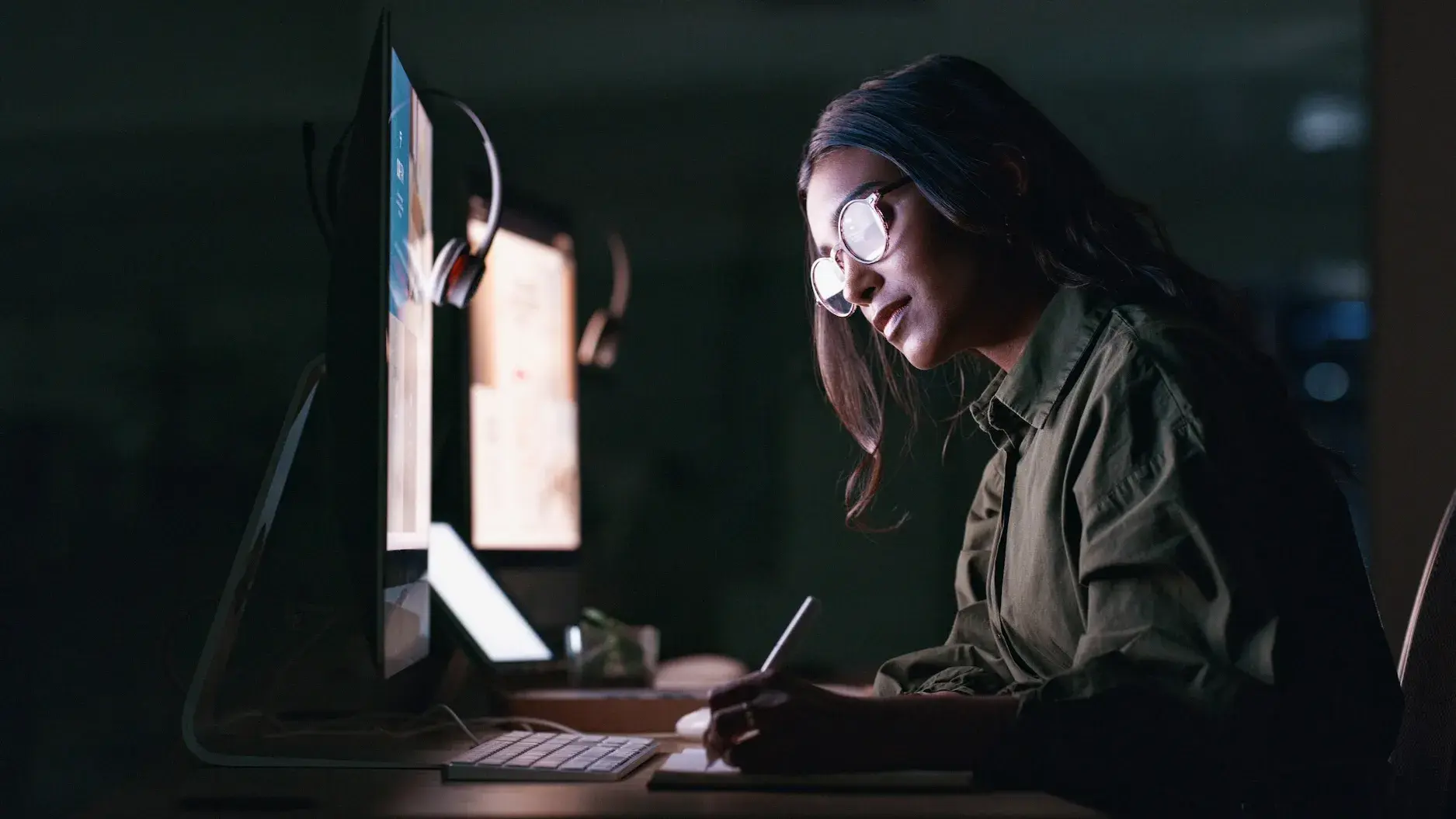 Person sitting in a dark room using computers