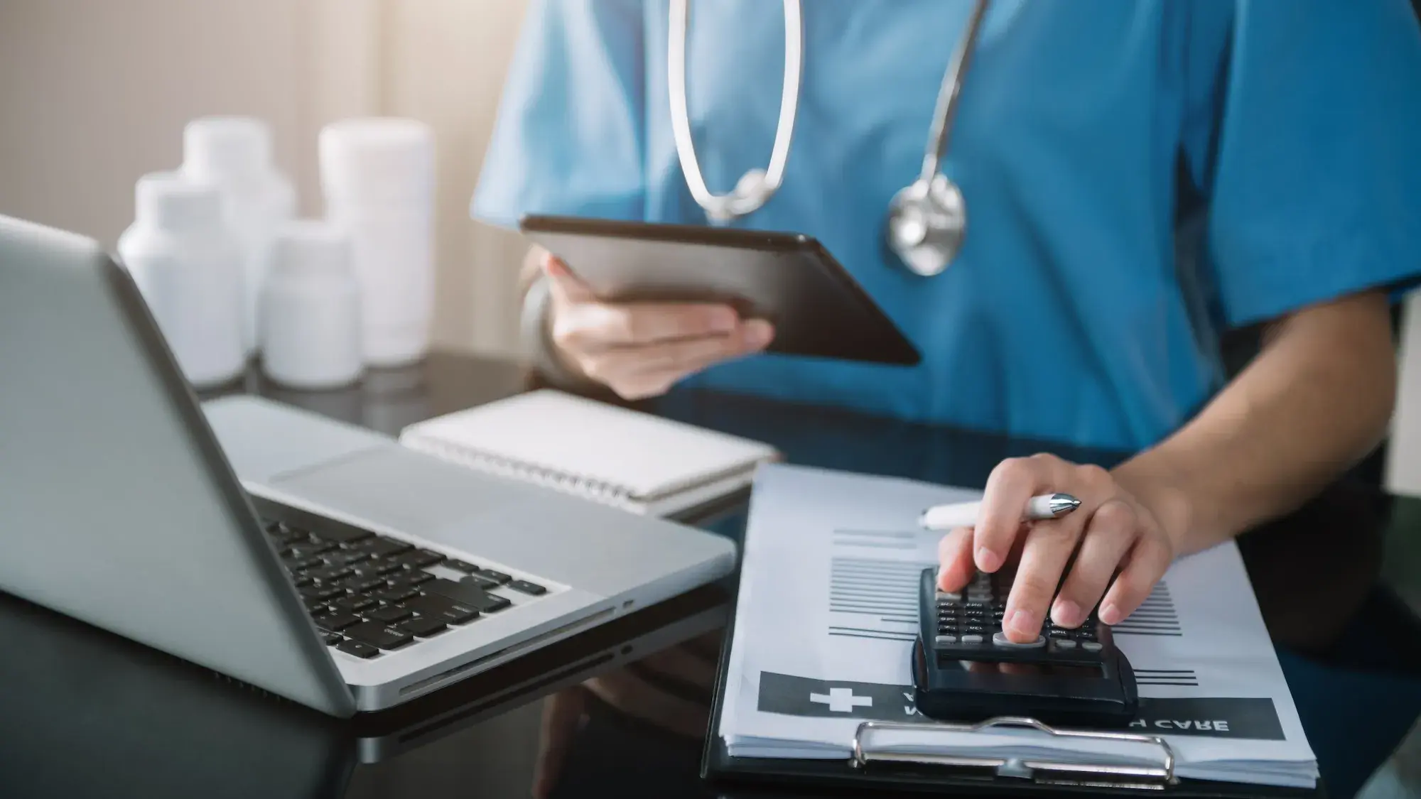 Nurse using laptop and calculator