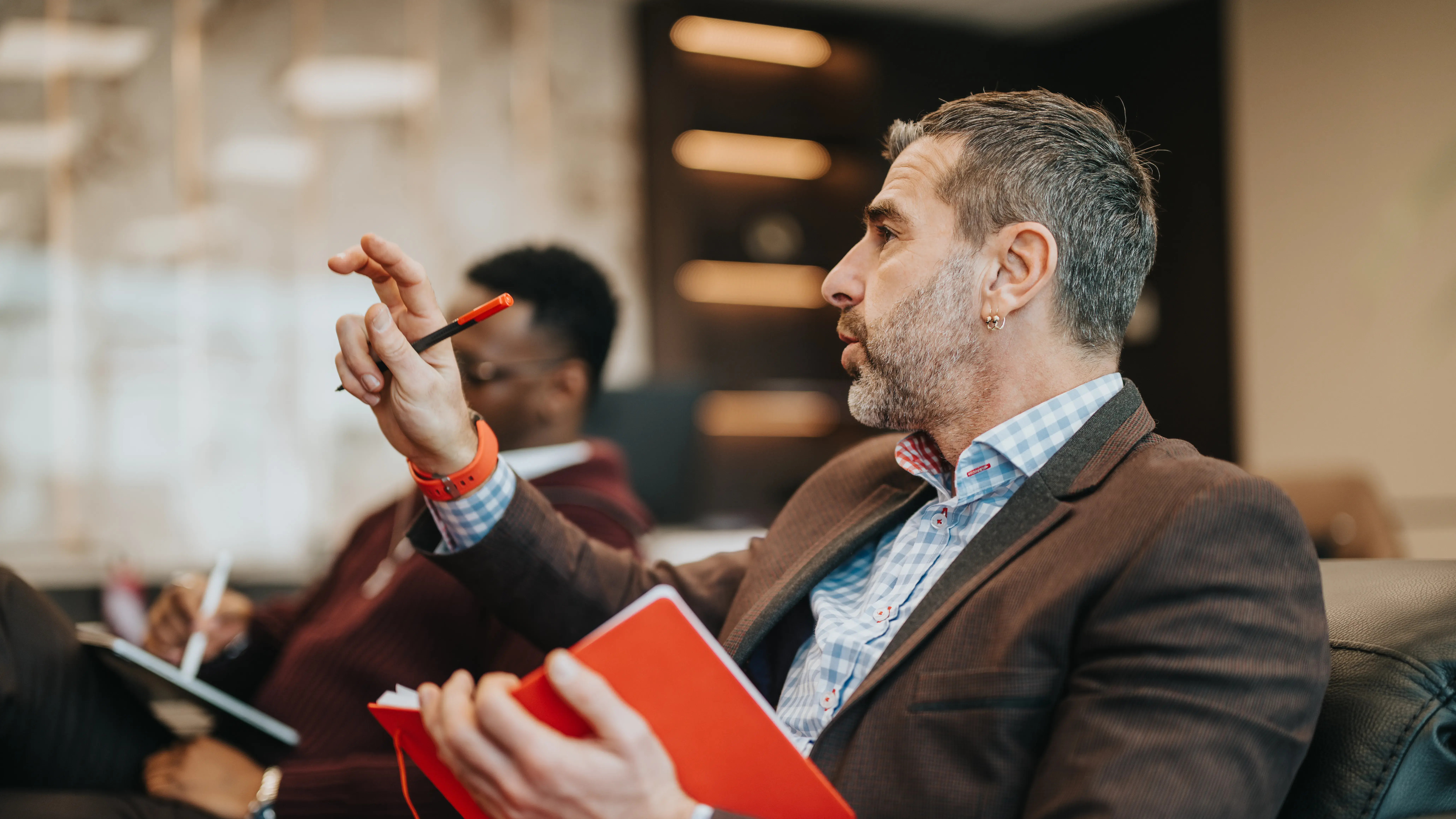 Business professional expressing ideas during a team discussion or meeting. Collaborative work environment with team members present.