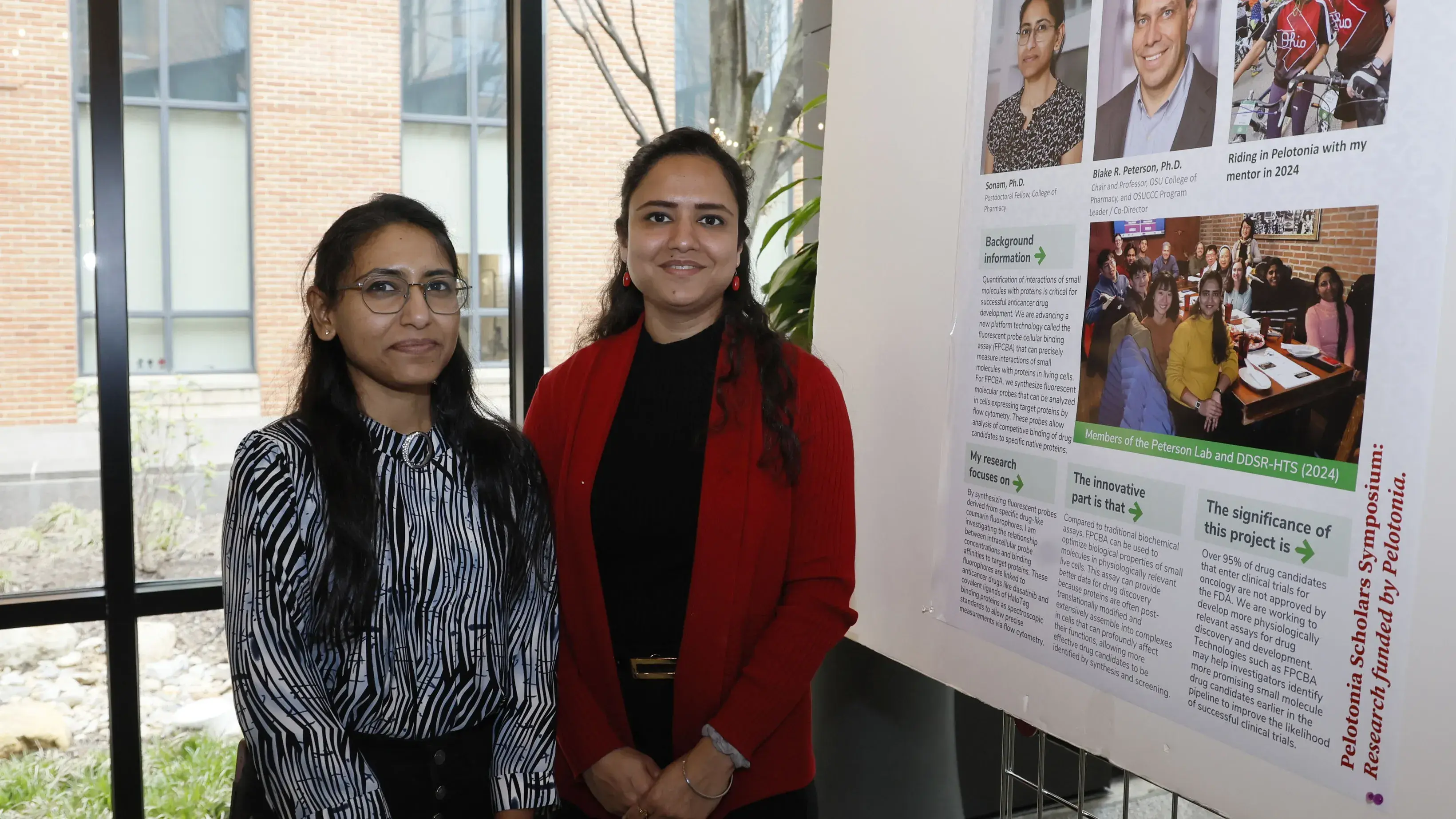women standing next to research poster