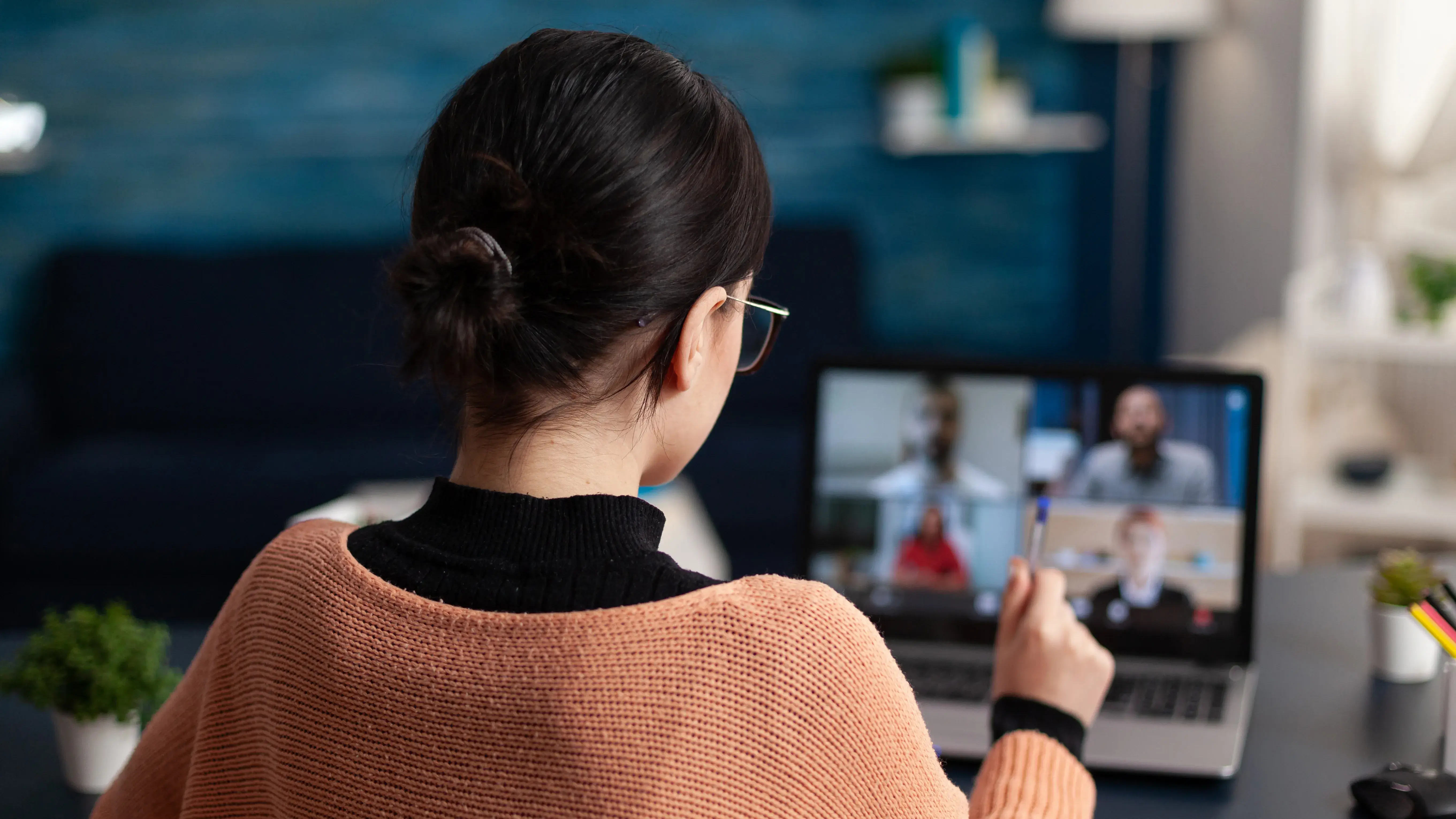 Person sitting at a desk participating in a video conference on a laptop