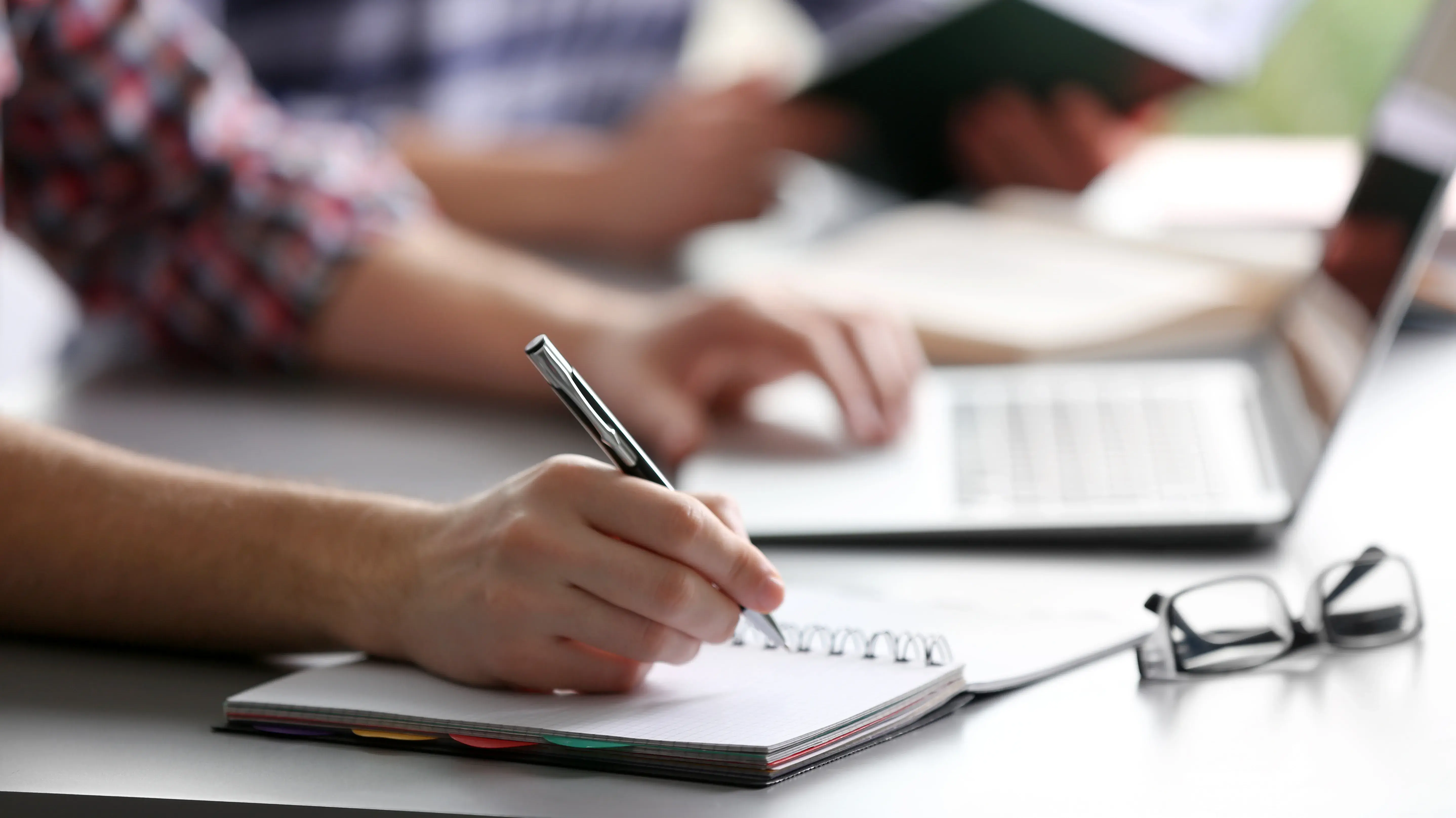 Student's hand writing in exercise book at the table