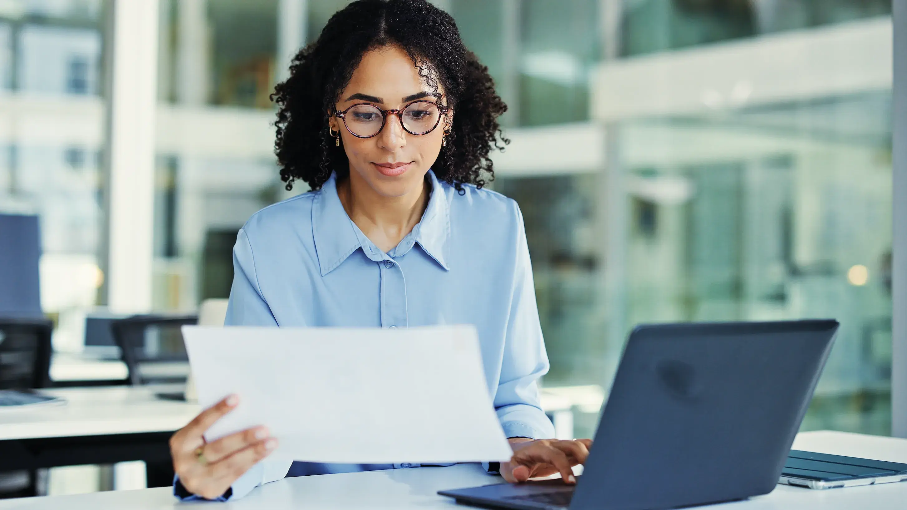 Woman reviewing papers at a computer